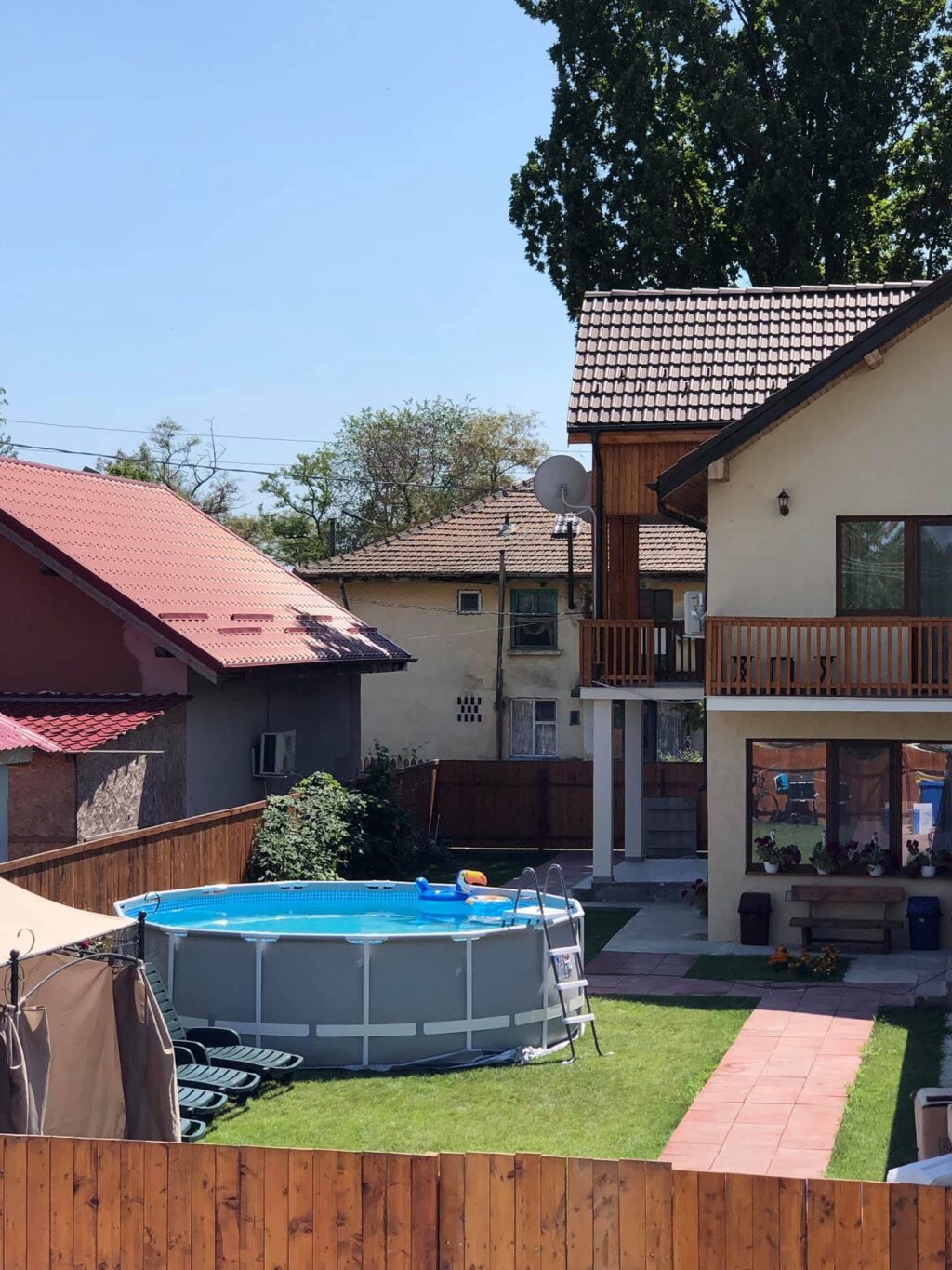 Balconul de lemn al pensiunii Casa Doi Stejari și acoperișurile satului Maliuc, văzute din curte