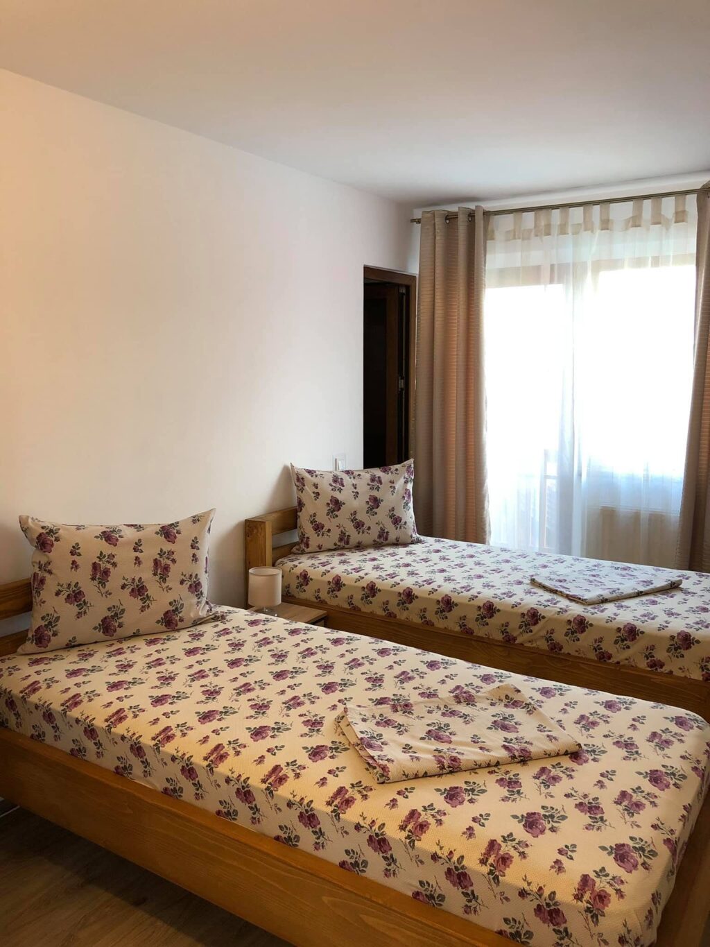 Cameră cu două paturi separate și lenjerie înflorată, la Casa Doi Stejari din Maliuc