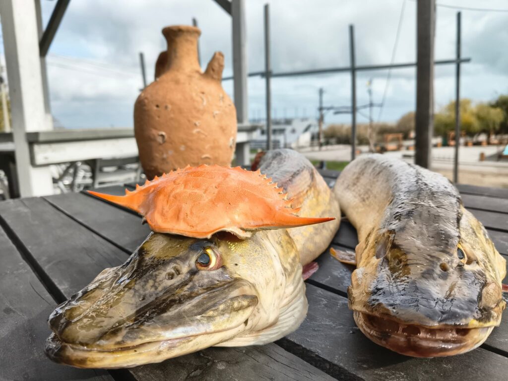 Crab și pește afumat pe masă de lemn, cu lacul Razim în fundal, la Taverna Le GaFish